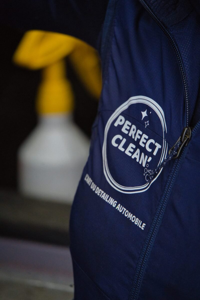Macro du logo 'Perfect Clean — L'art du detailing automobile' brodé sur la veste de l'équipe