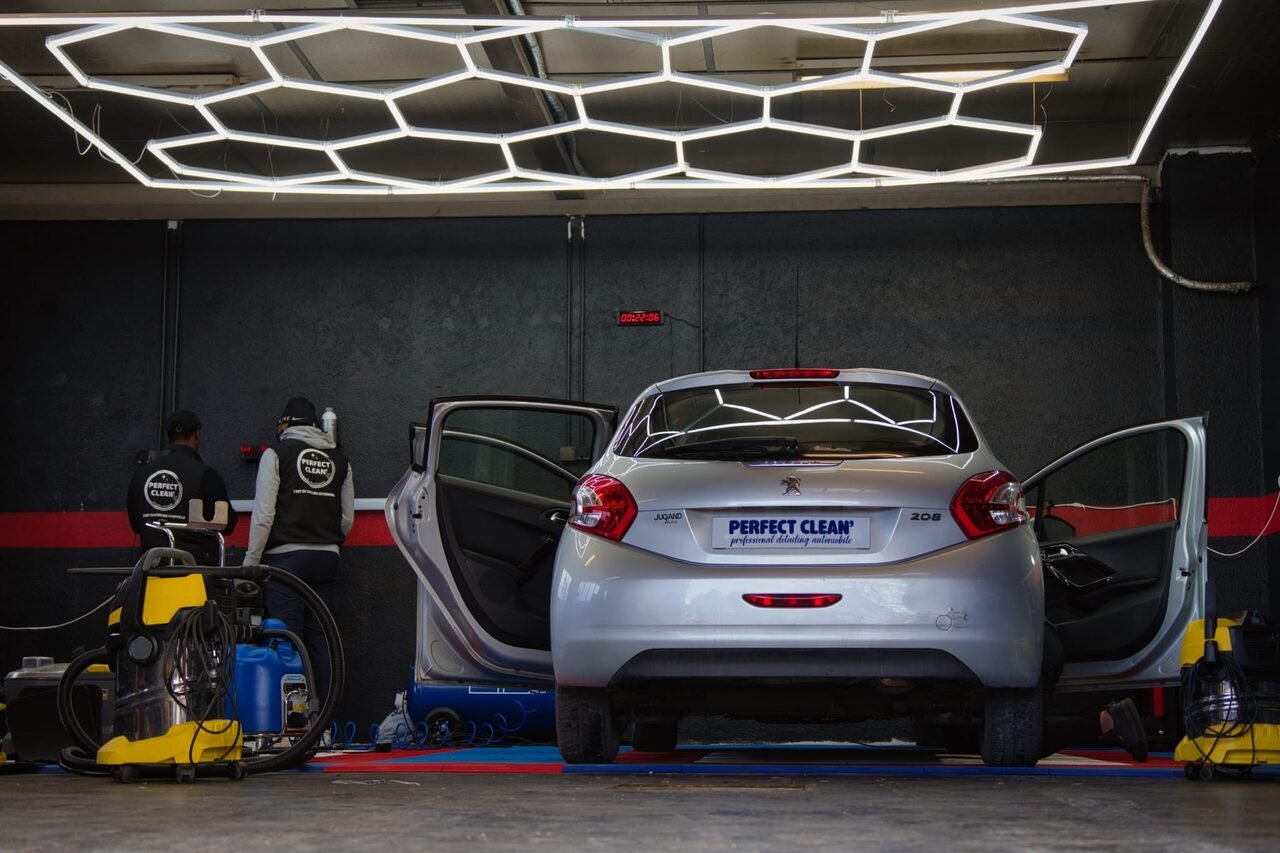 Vue large : deux opérateurs travaillant à l'arrière de la Peugeot 208 sous la rampe LED