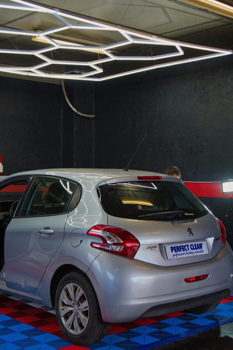 Trois-quarts arrière gauche de la Peugeot 208 sous l'éclairage LED hexagonal de l'atelier